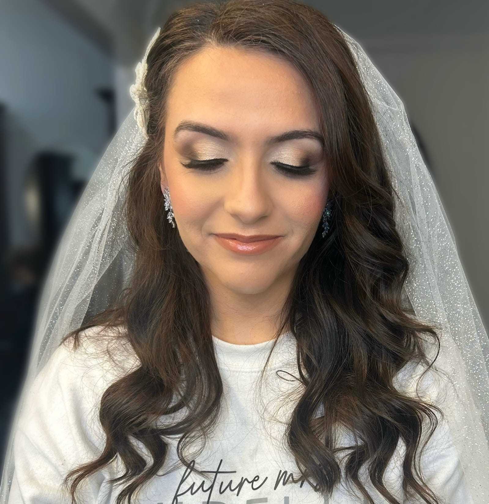 Bride with wavy hair and veil in a serene, elegant moment, ready for her wedding day.